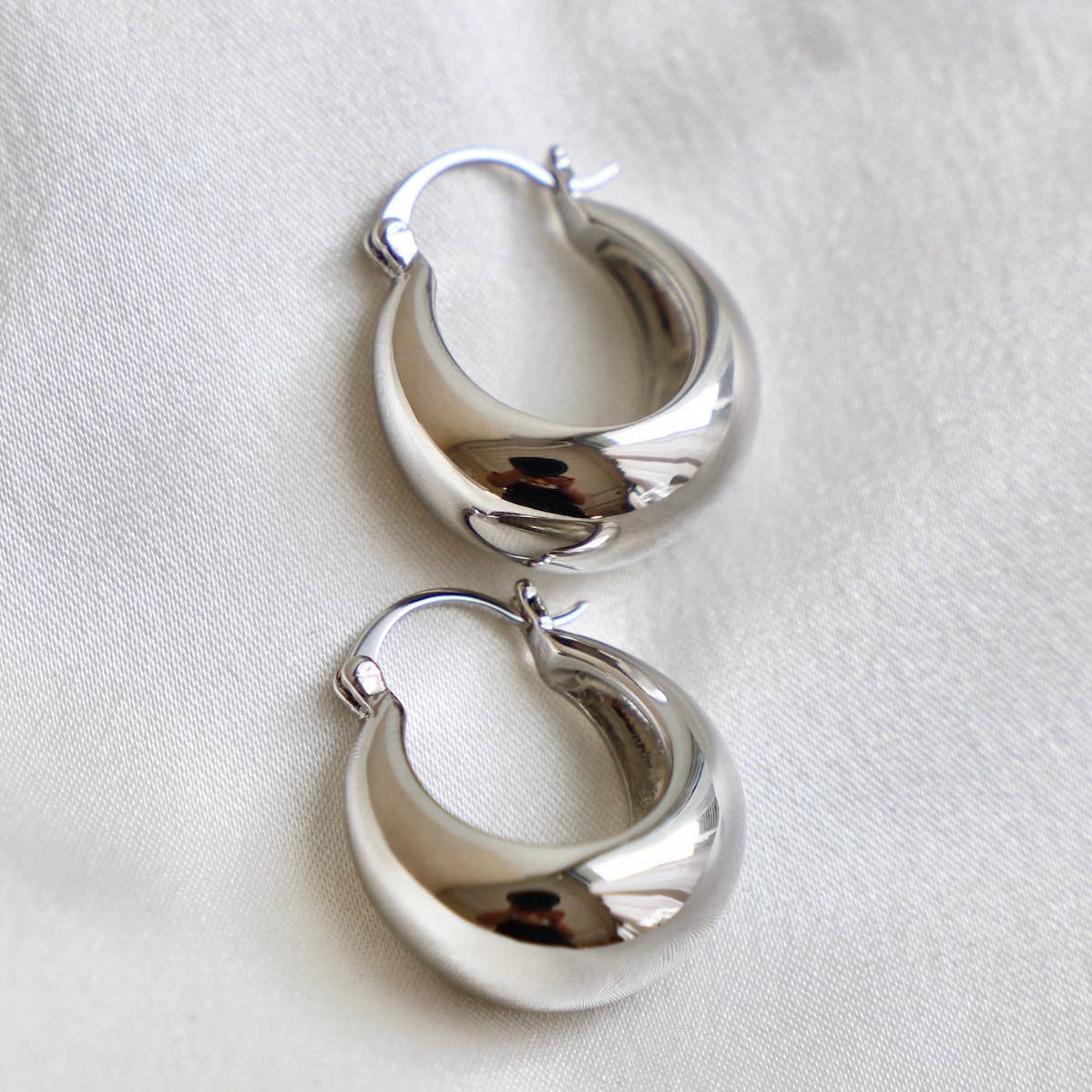 Pair of silver hoop earrings on a light fabric background