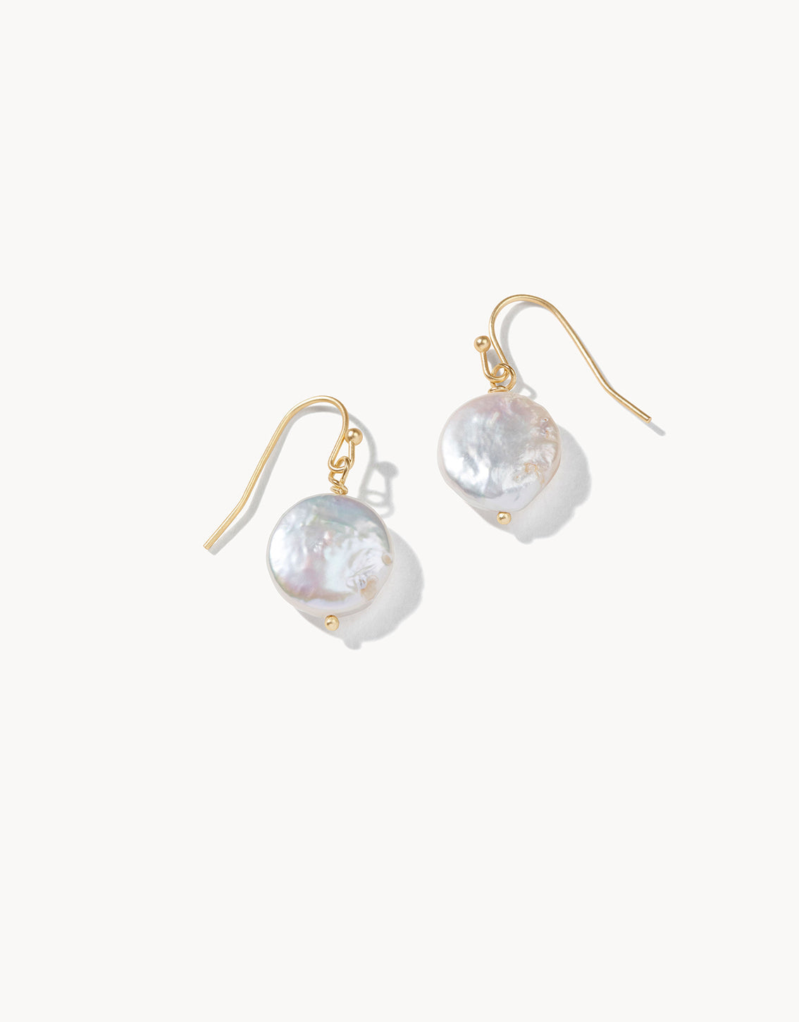 Pair of pearl earrings with gold hooks on a white background
