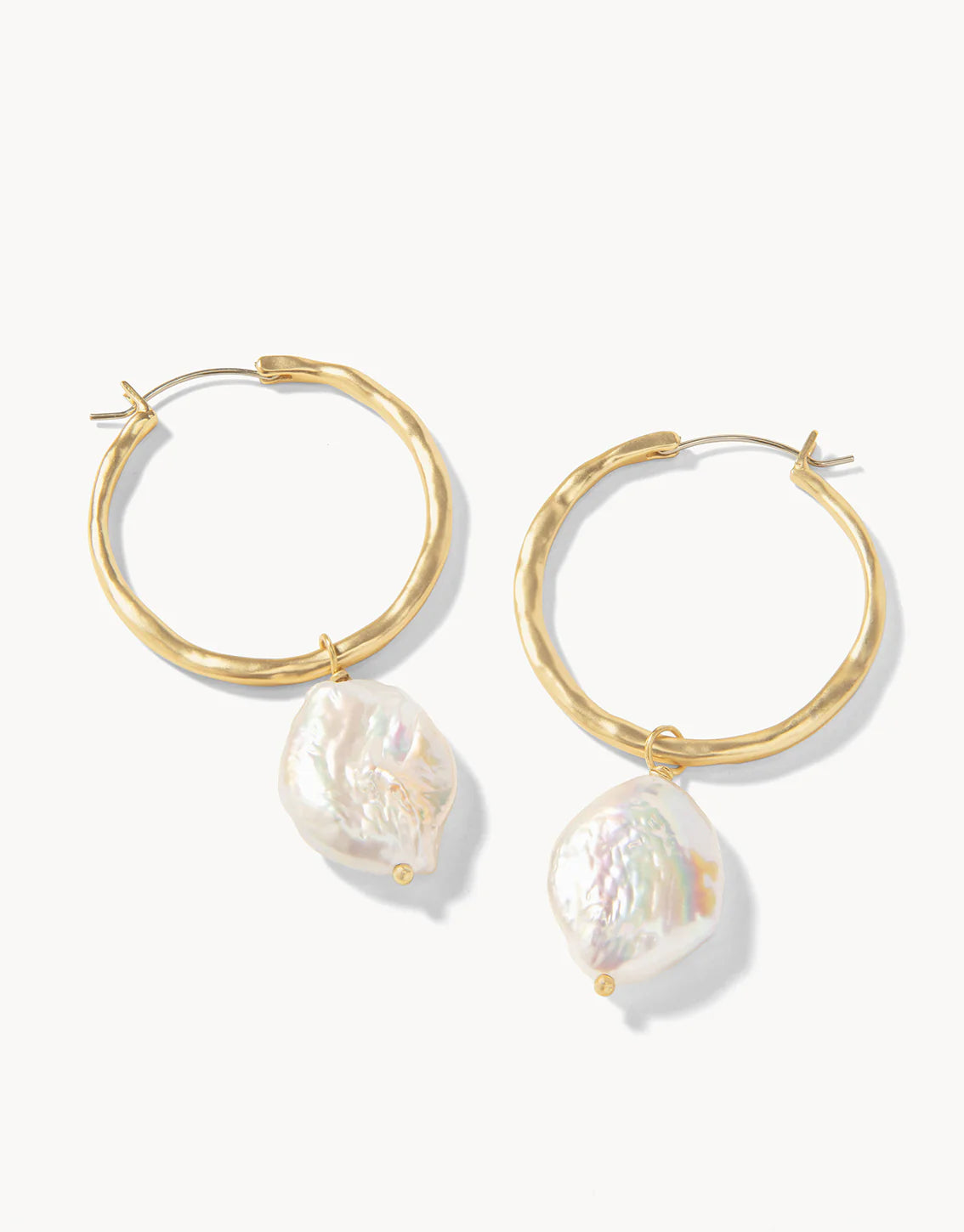 A pair of gold hoop earrings with pearl drops attached to them, displayed against a white background.