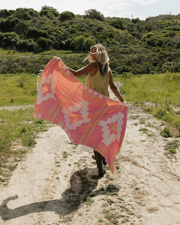 Person holding a colorful towel in a natural setting with greenery