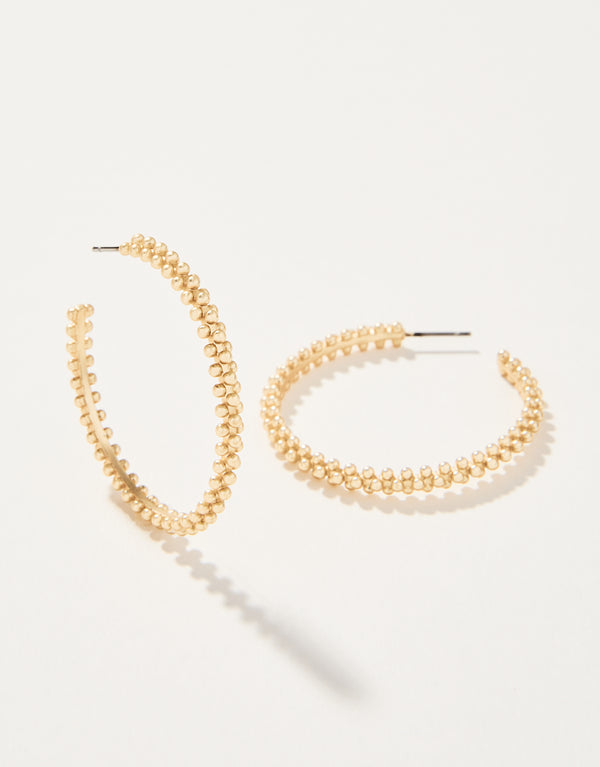 A pair of gold-colored hoop earrings with beaded details on a white background.