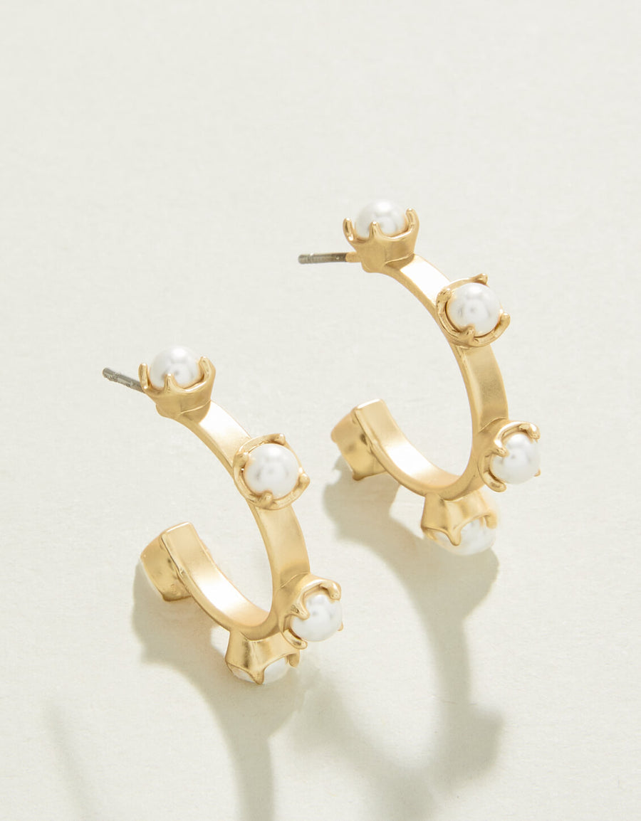 A pair of gold-colored midi hoop earrings with faux pearl accents on a white background.