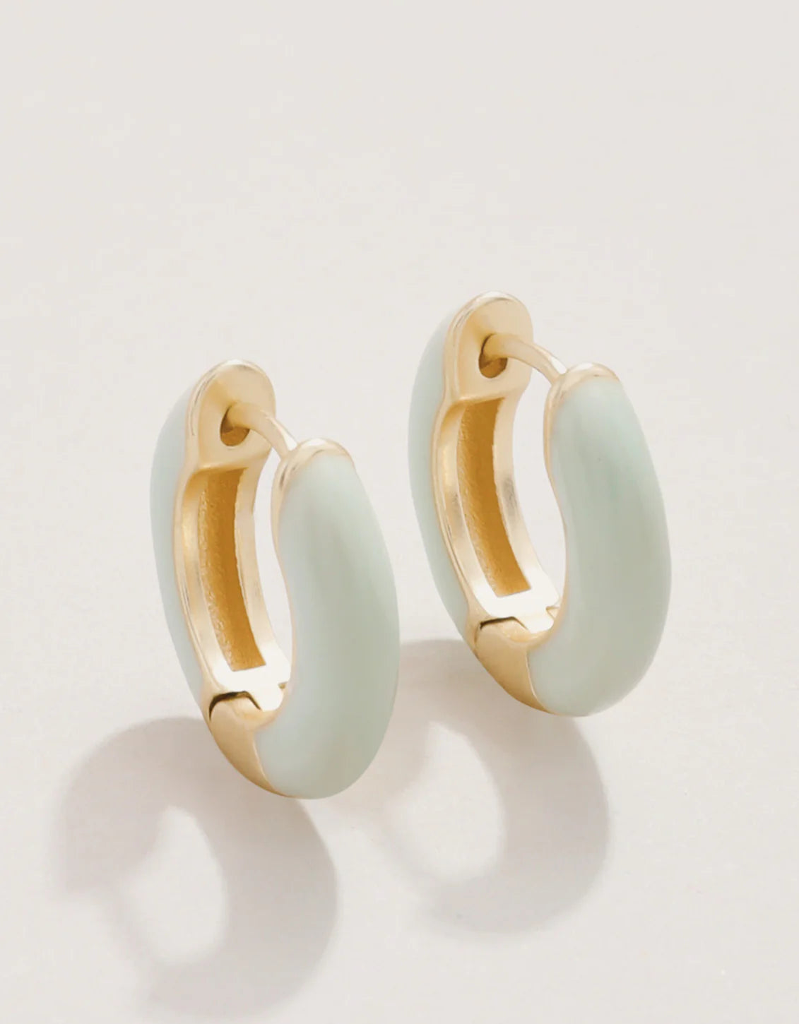 A pair of gold-plated hoop earrings with sea foam green enamel.
