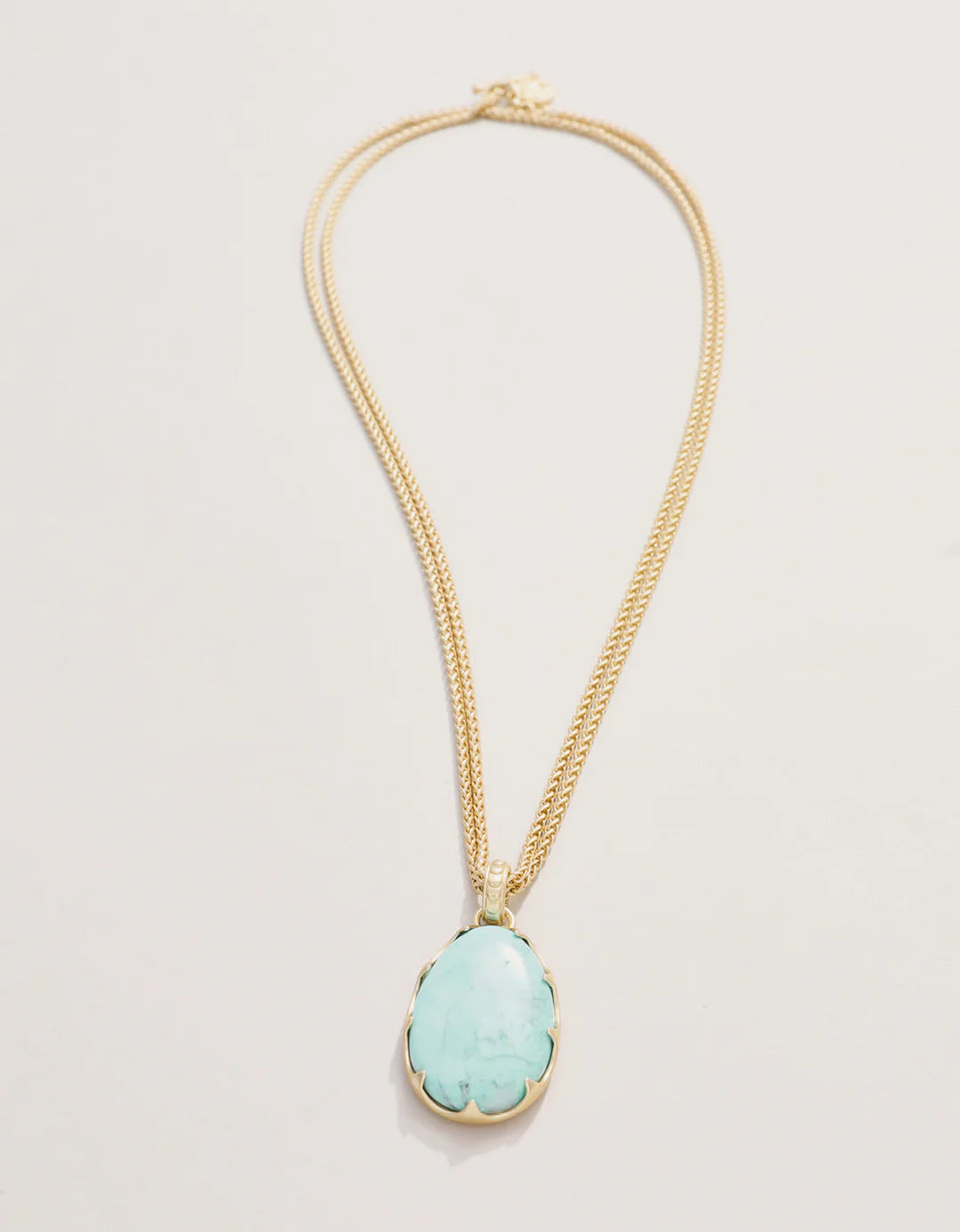 Necklace with a turquoise pendant on a light beige background