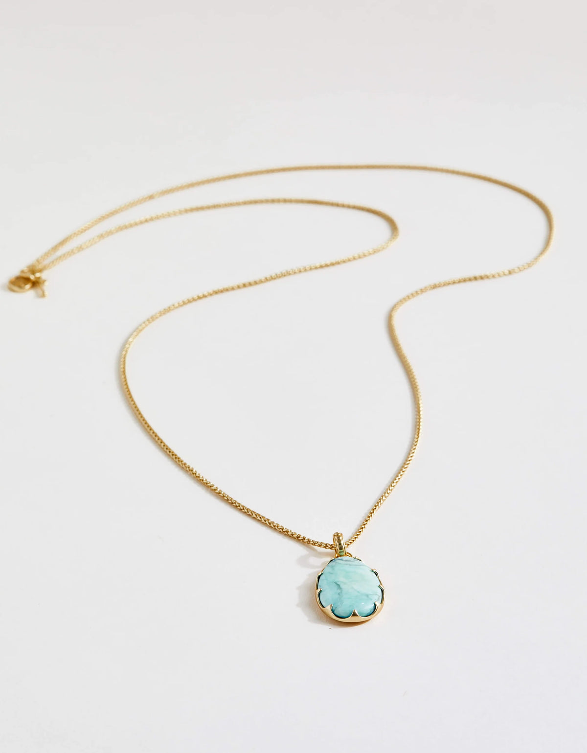 Gold necklace with a turquoise pendant on a white background