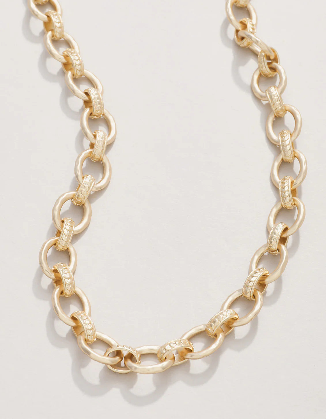 A gold chain necklace with a spring ring clasp, displayed against a white background.