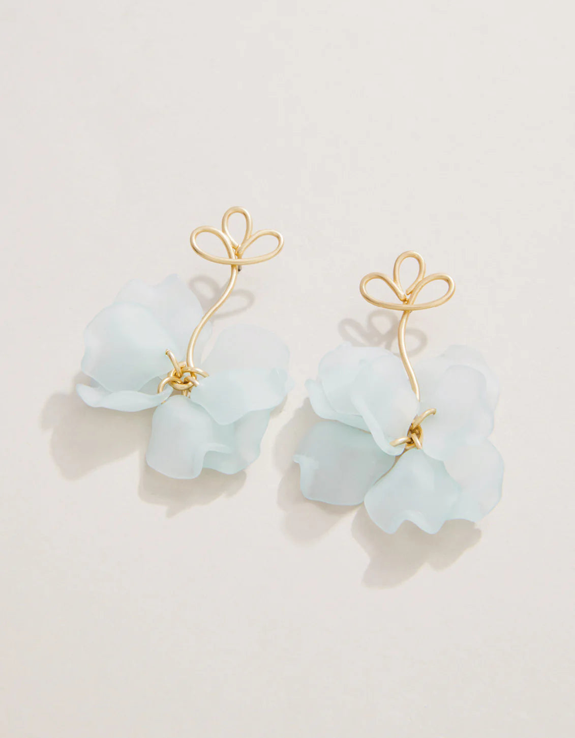 A pair of blue floral earrings with gold stems and petals on a white background.