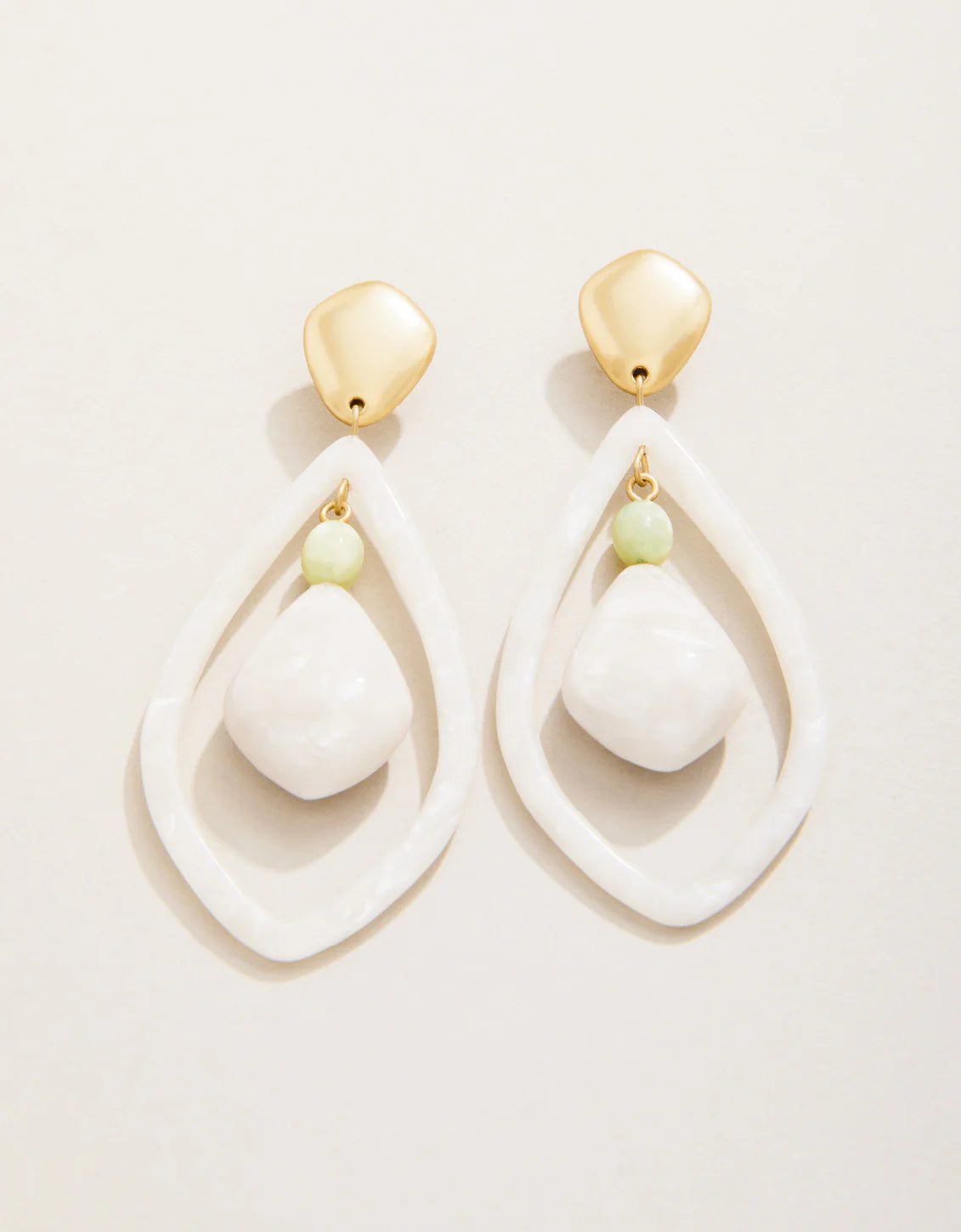 A pair of pearlescent white and gold earrings with a teardrop shape and small bead detail.