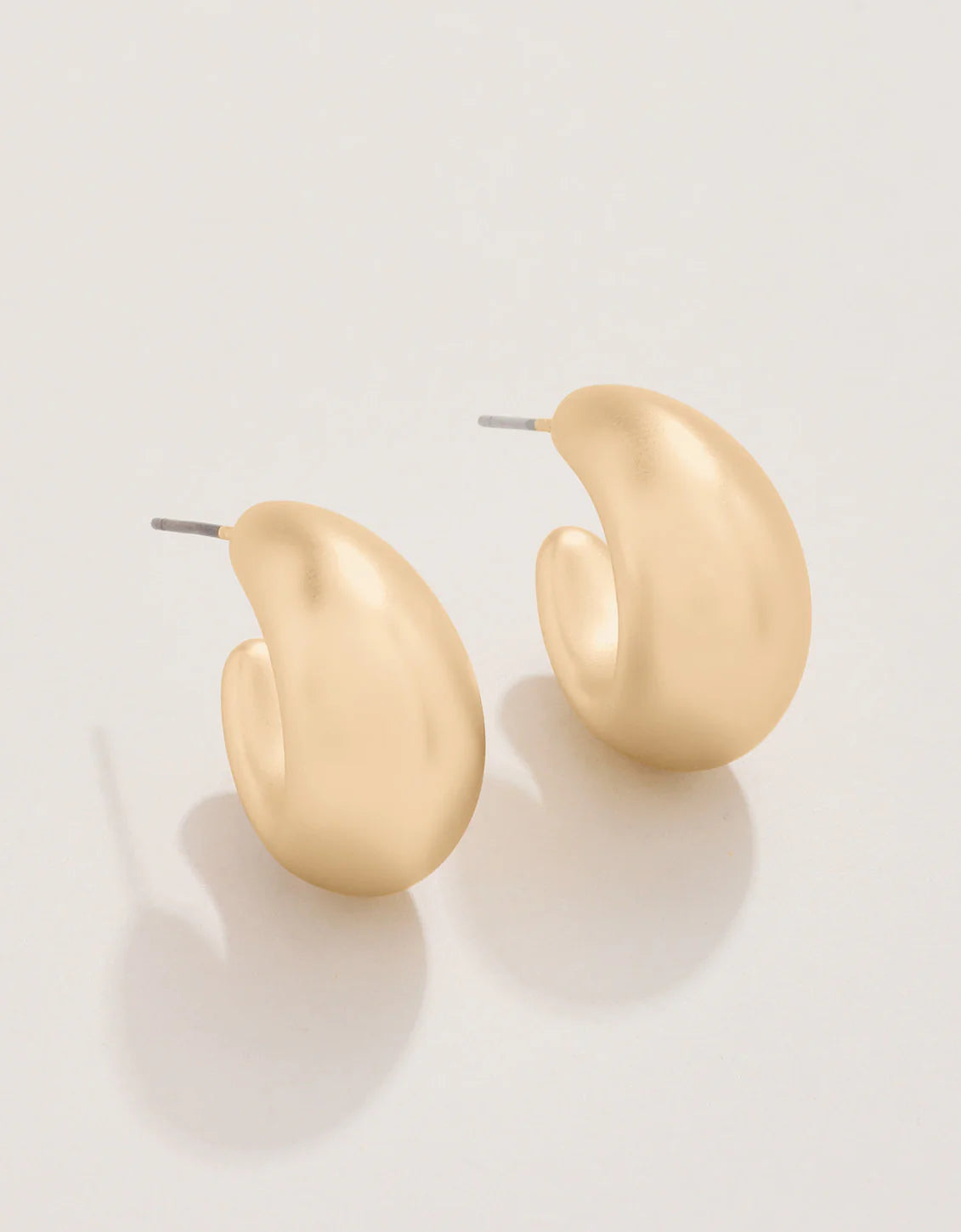 A pair of 18kt matte gold plated plastic hoop earrings on a white background.