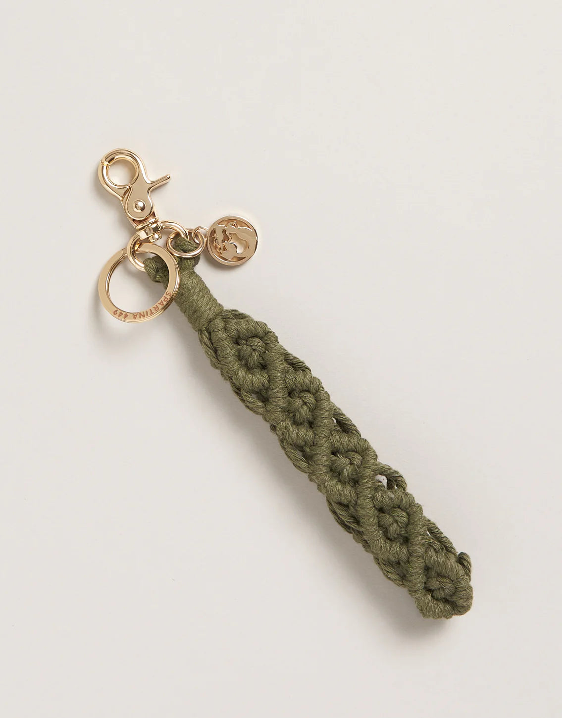 An olive green macrame wristlet keychain with a metal ring and charm.
