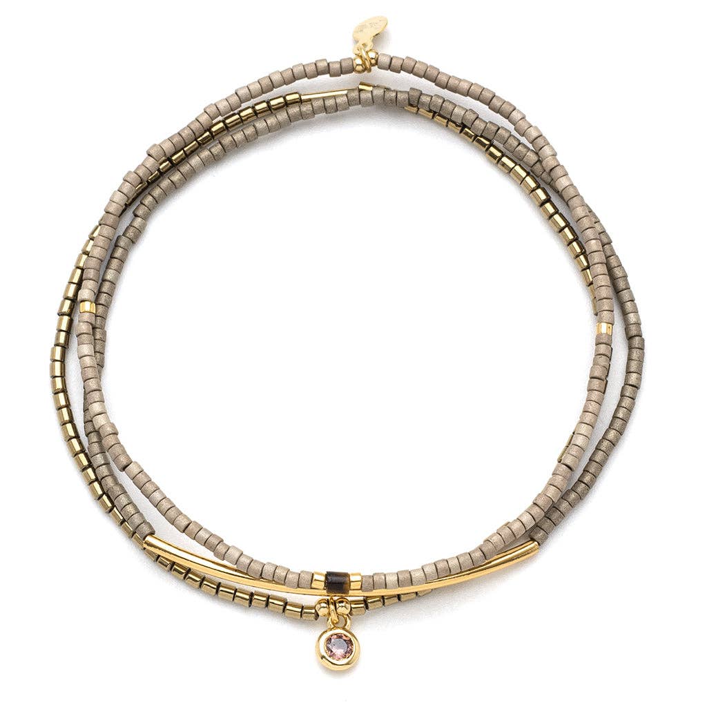 A trio of stacking bracelets featuring gold and pewter colors with textured beads and a small rhinestone charm.