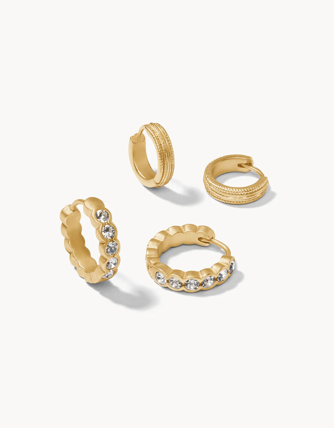 A set of gold-colored hoop earrings with one pair featuring a textured design and the other pair adorned with gemstones.