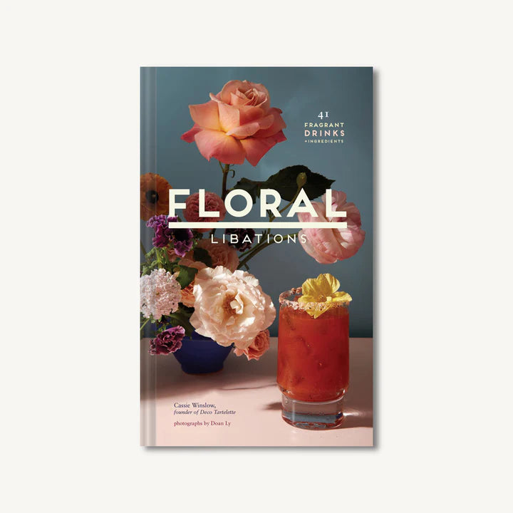 A book cover of 'Floral Libations' featuring a title and an image of a glass with a pink flower decoration, surrounded by other flowers and a blue background.