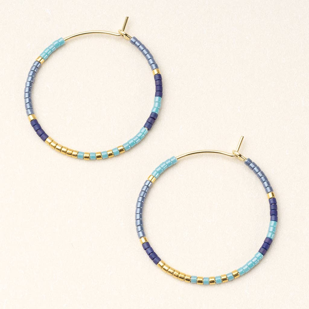 A pair of round earrings with cobalt blue and gold colored beads, finished with gold or silver dipped brass.
