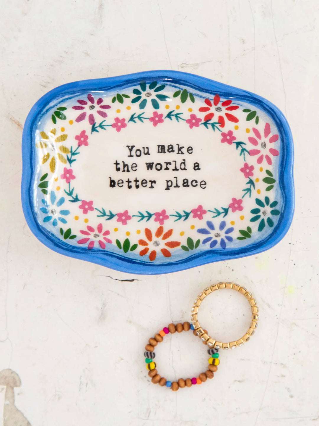 Decorative tray with floral design and motivational quote, accompanied by a bracelet on a light background