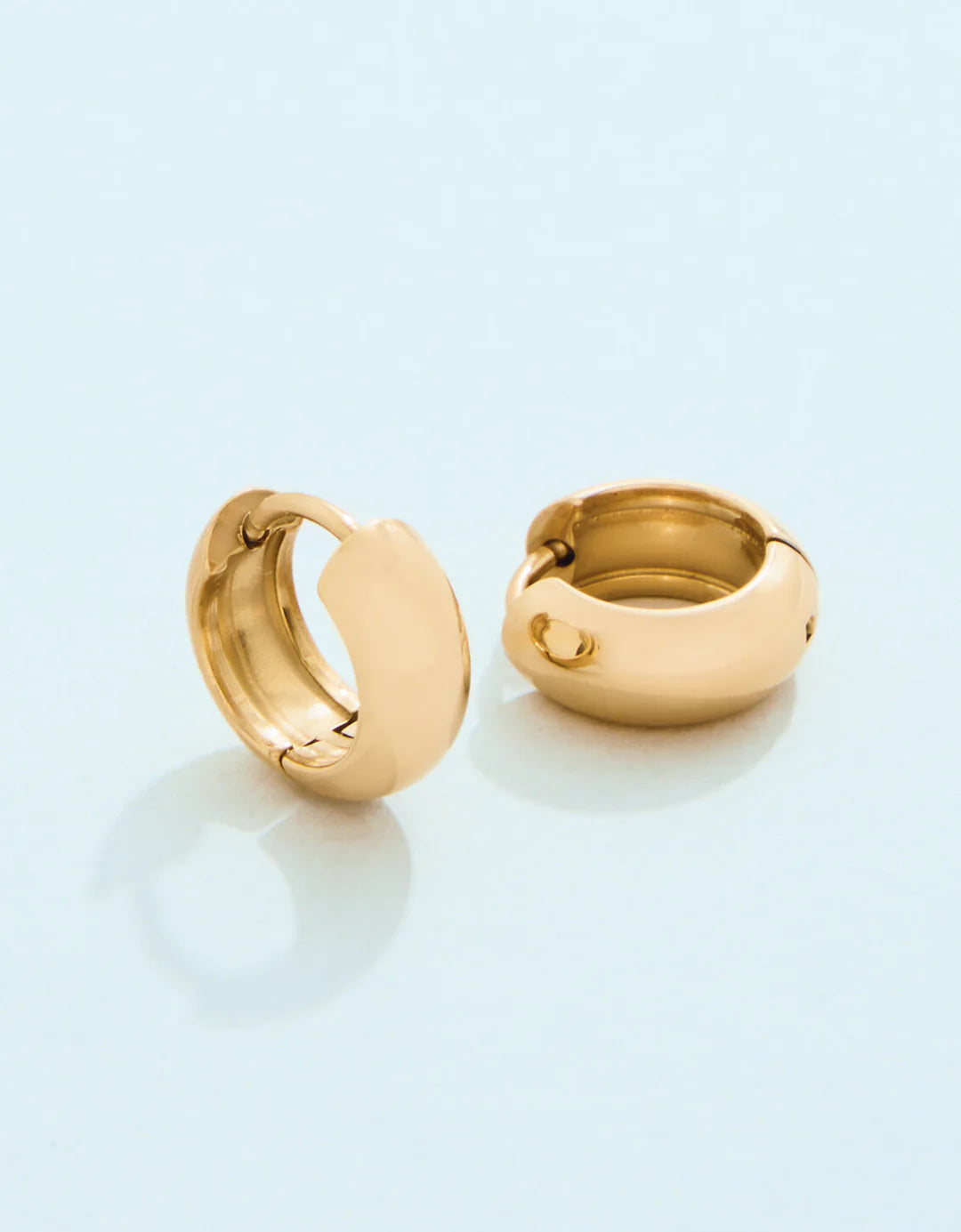 Pair of gold hoop earrings on a light blue background