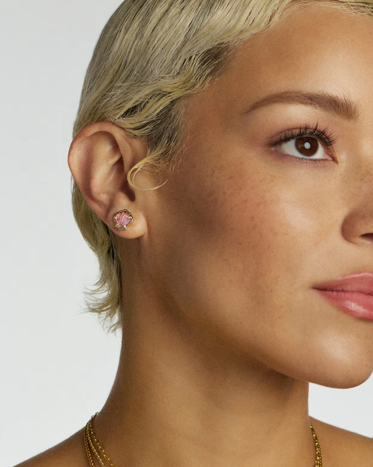 Close-up of a woman wearing pink earrings with a white background