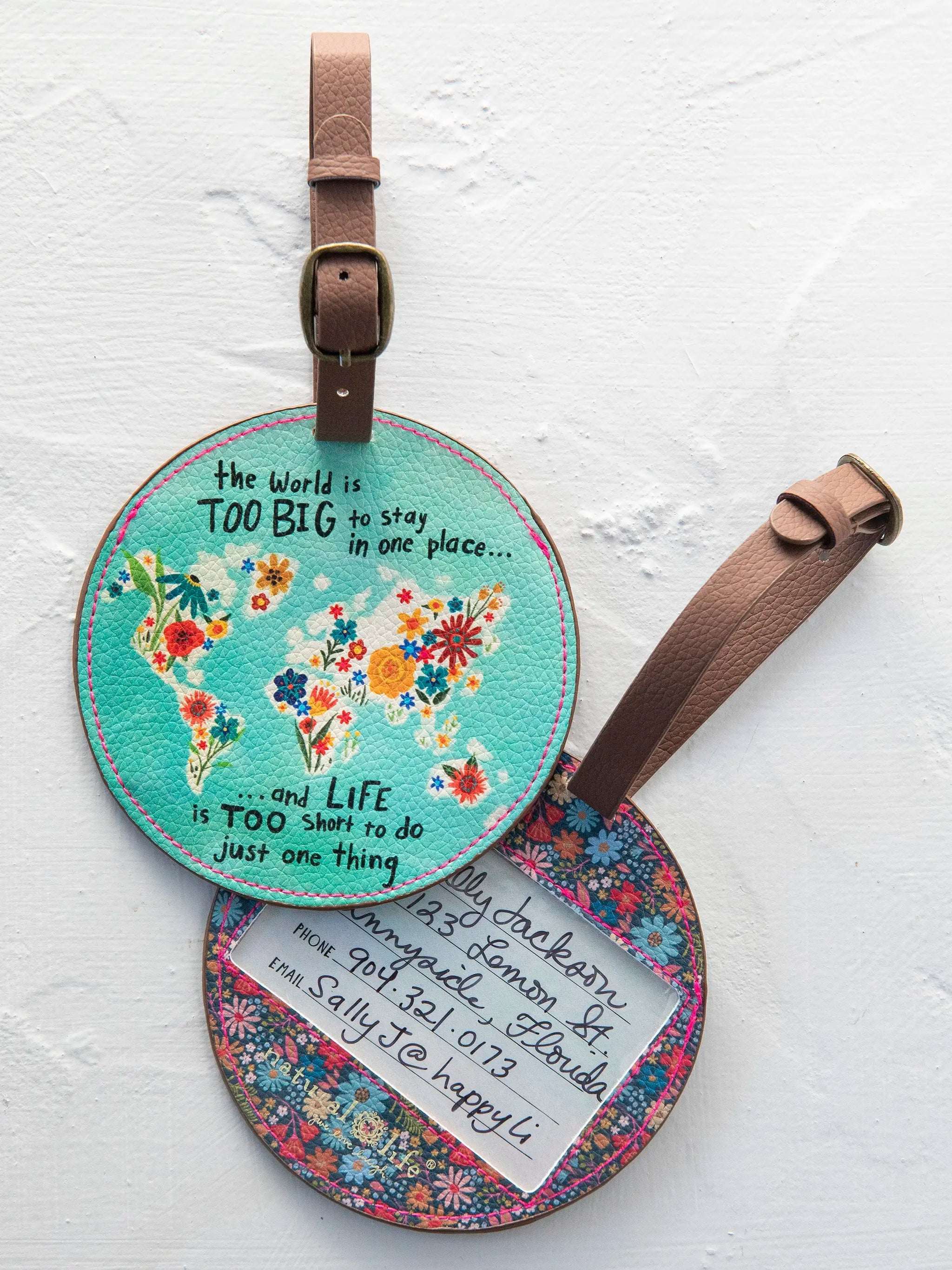 Round floral world map luggage tag with text on a white background