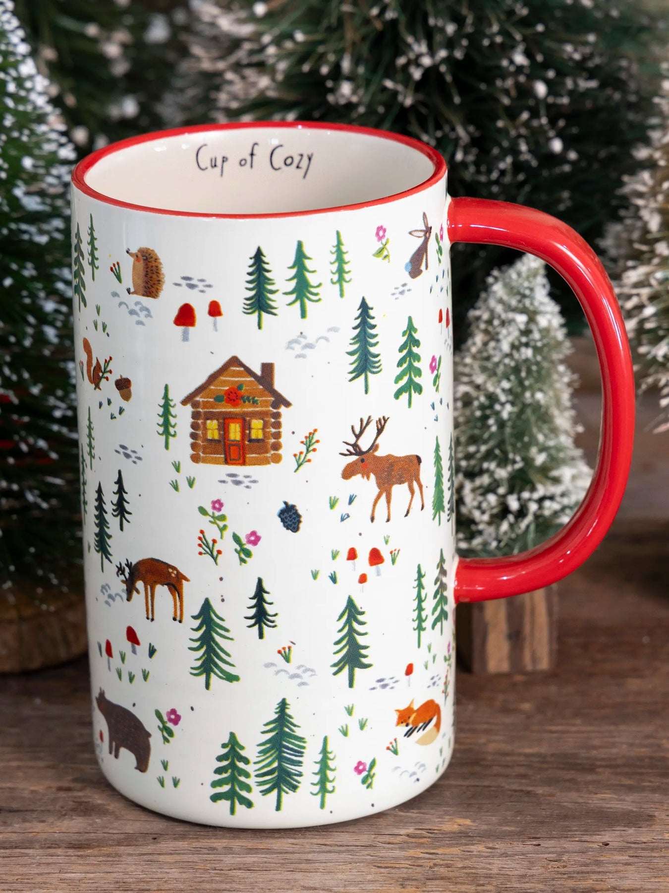 Mug with red handle and nature-themed design on a wooden surface