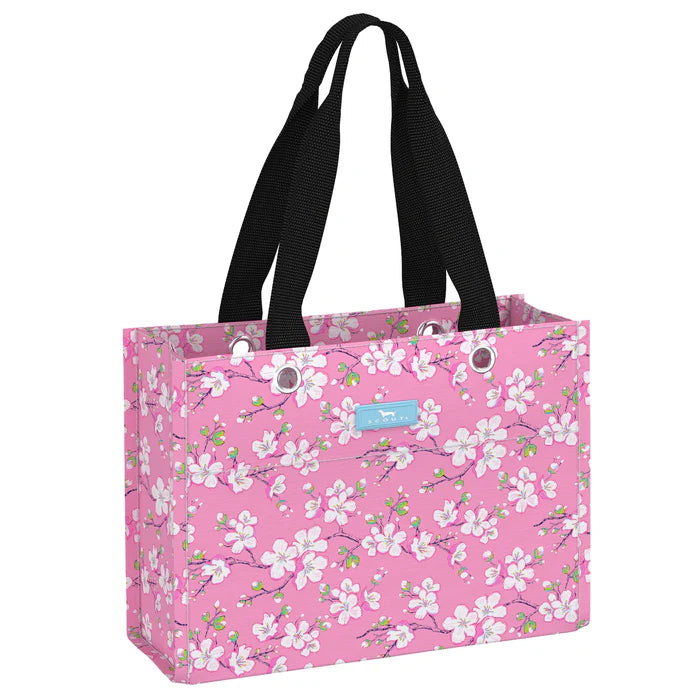 A pink gift bag with a floral pattern, black handles, and a brand tag displaying 'Scout Bags'.