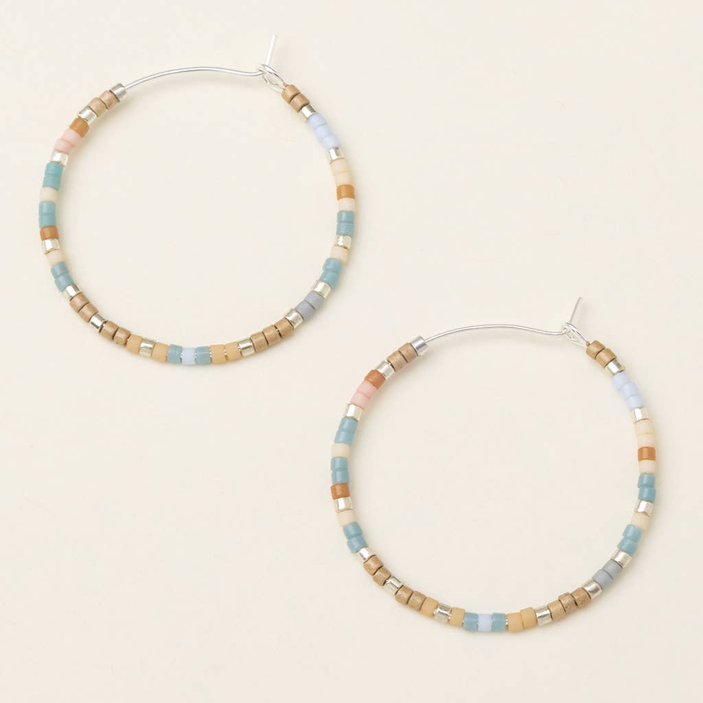 A pair of round earrings with a mix of desert blue and silver colors, made from brass nickel and cadmium-free hypoallergenic material.
