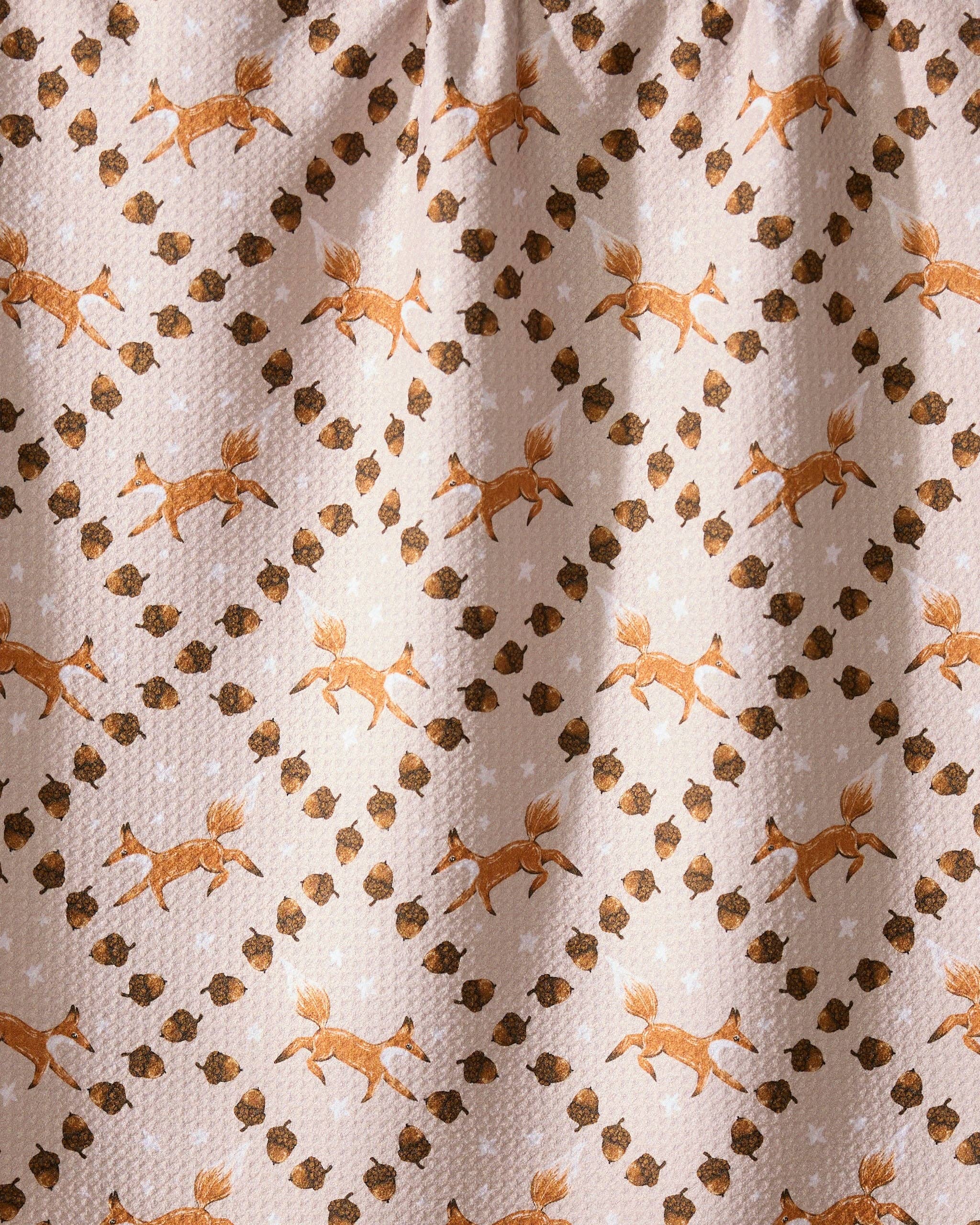 Fabric with a pattern of deer and acorns on a beige background