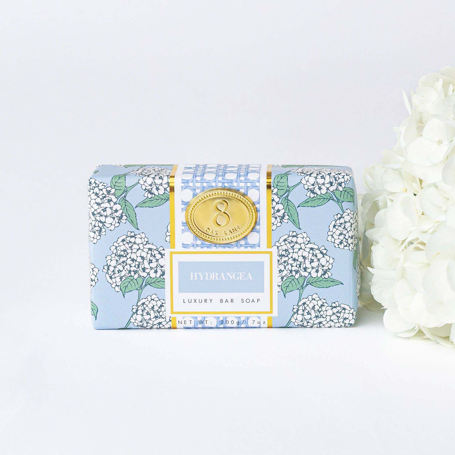 A bar of soap with a blue and green hydrangea floral print wrapper, with a gold seal in the center. The word 'HYDRANGEA' is prominently displayed at the top.