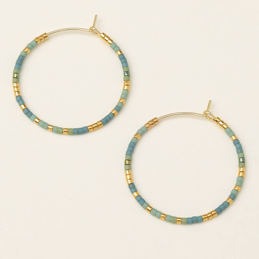 A pair of turquoise and gold hoop earrings on a white background