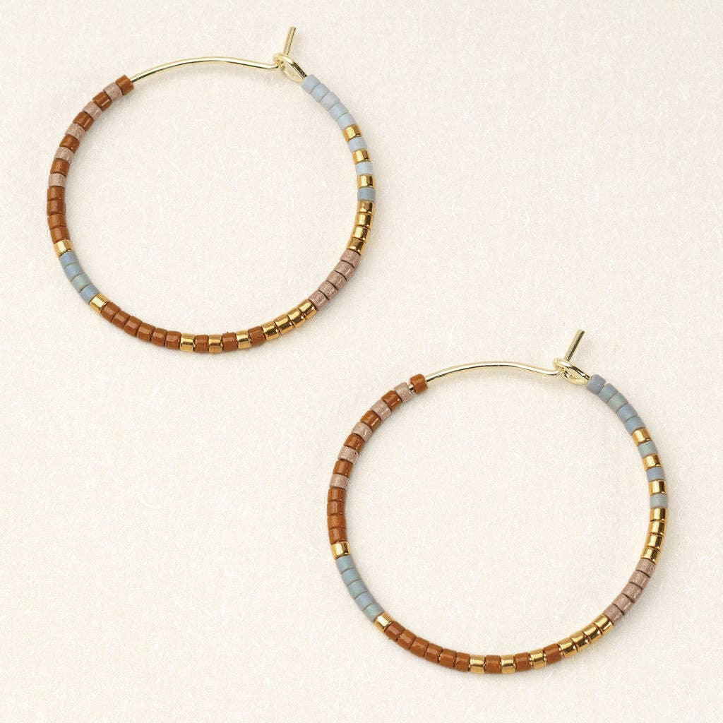 A pair of round hoop earrings with desert multi and gold color beads, dipped in gold or silver, on a white background.
