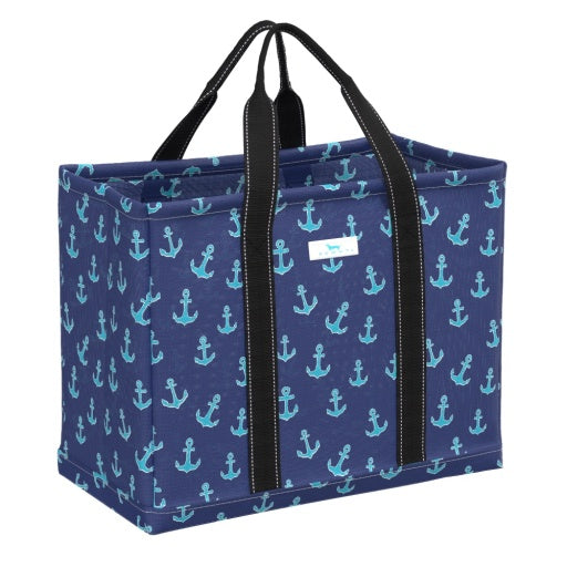 A navy blue tote bag with a striped pattern featuring anchors, with black straps and a white brand tag on the side.