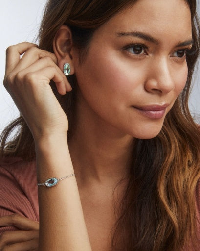 Woman wearing a bracelet and earrings with a neutral background