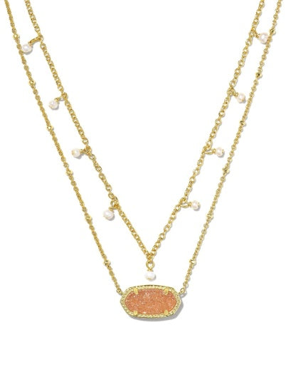 Two gold necklaces with a central peach-colored stone and small pearls on a white background