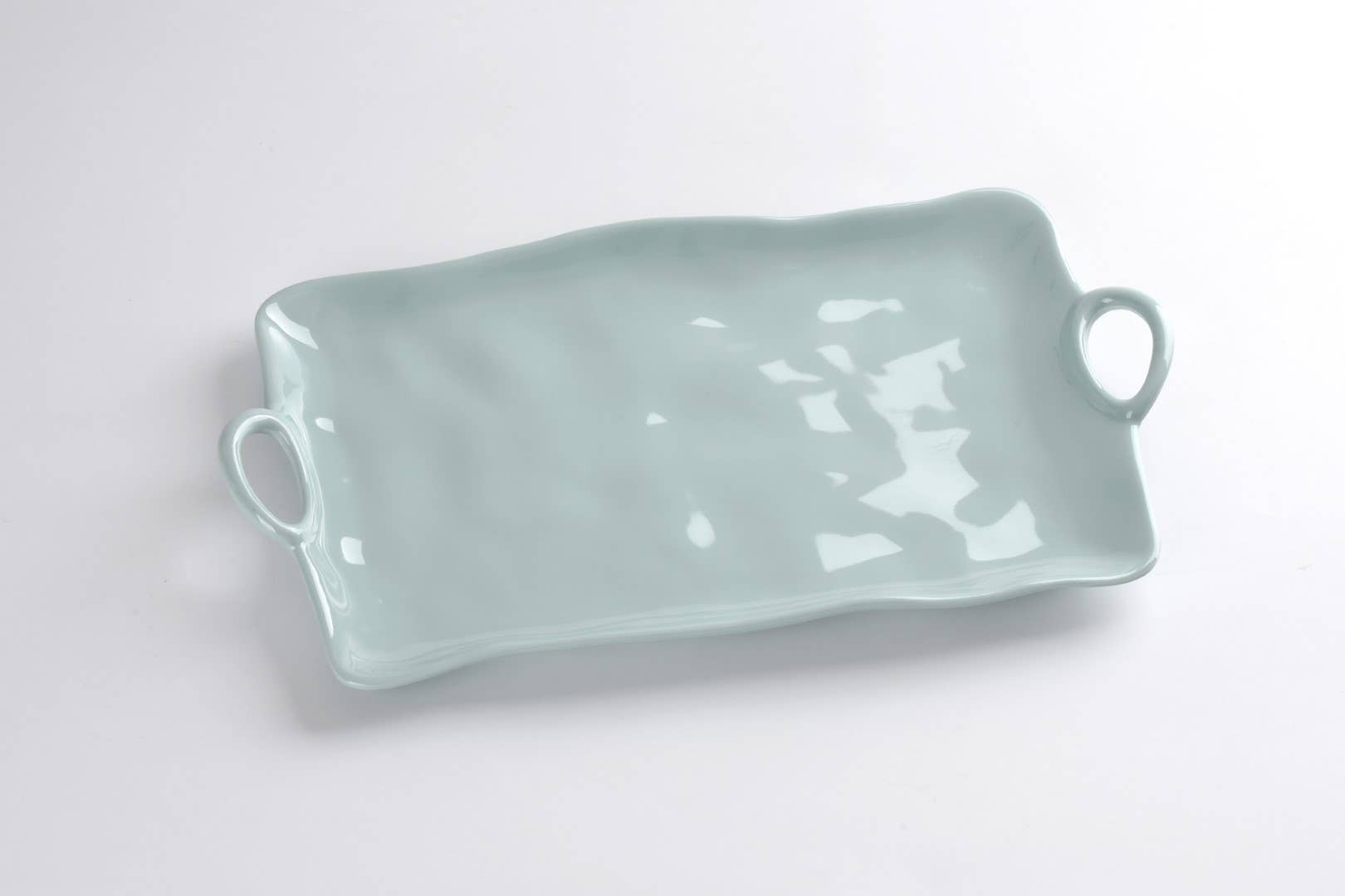 Rectangular ceramic tray with handles on a light gray background