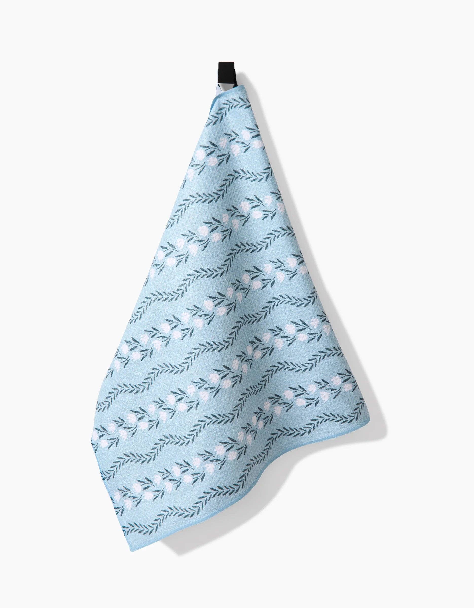 Light blue towel with leaf pattern hanging on a white background