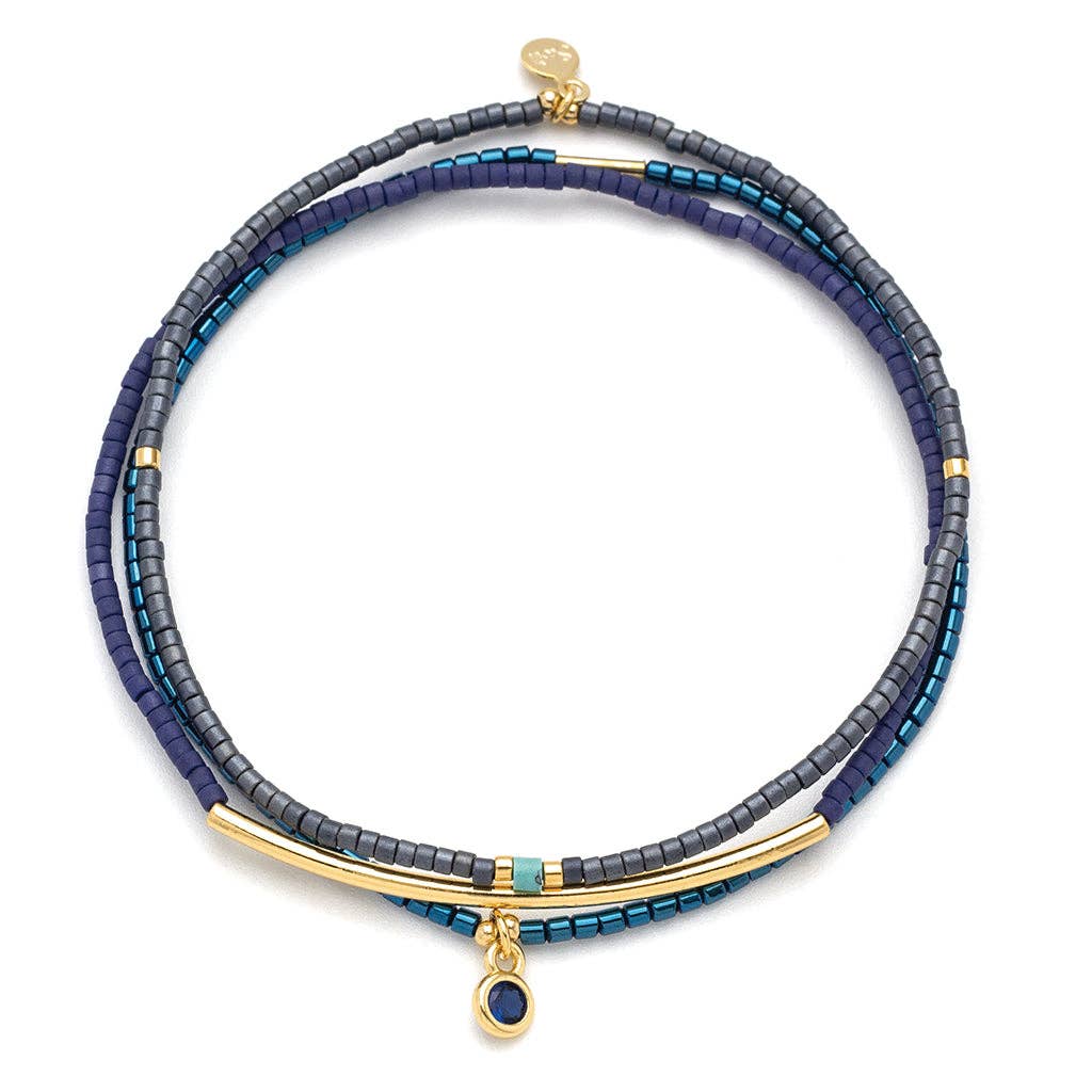 A navy and gold Miyuki Delica bead bracelet with textured design and a tiny rhinestone charm, displayed on a white background.