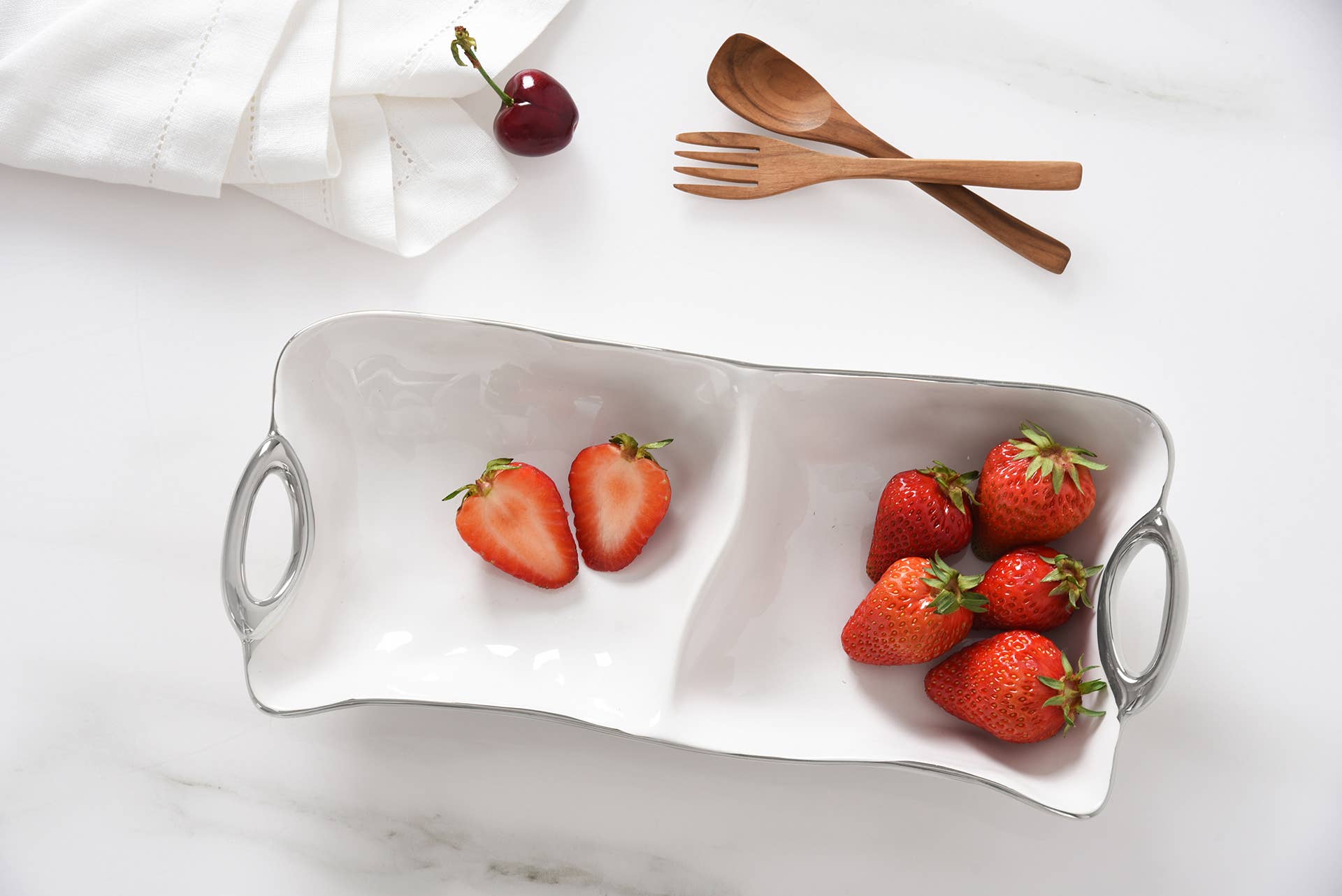 White ceramic dish with strawberries on a white marble surface