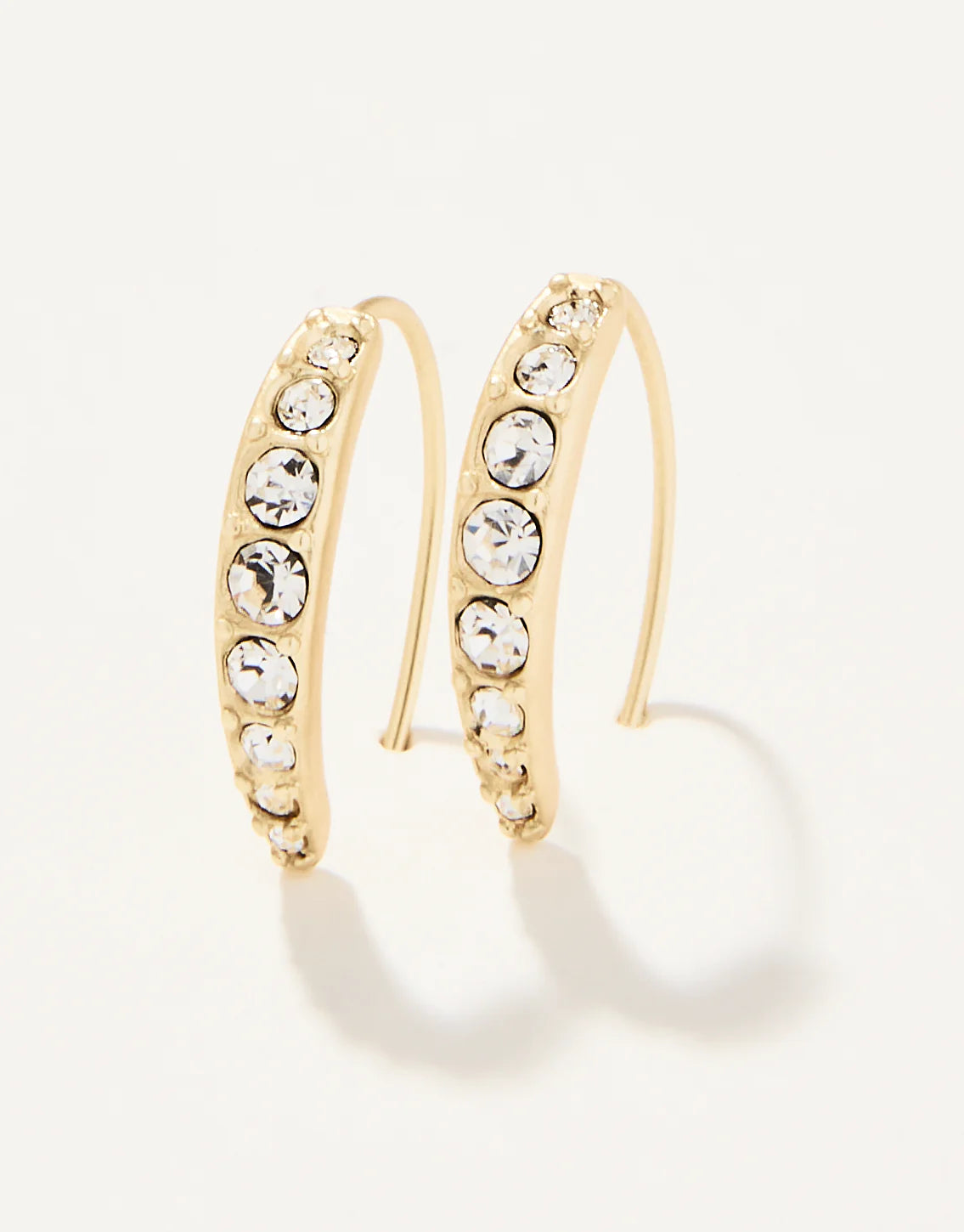 A pair of gold-colored hoop earrings with crystal embellishments on a white background.