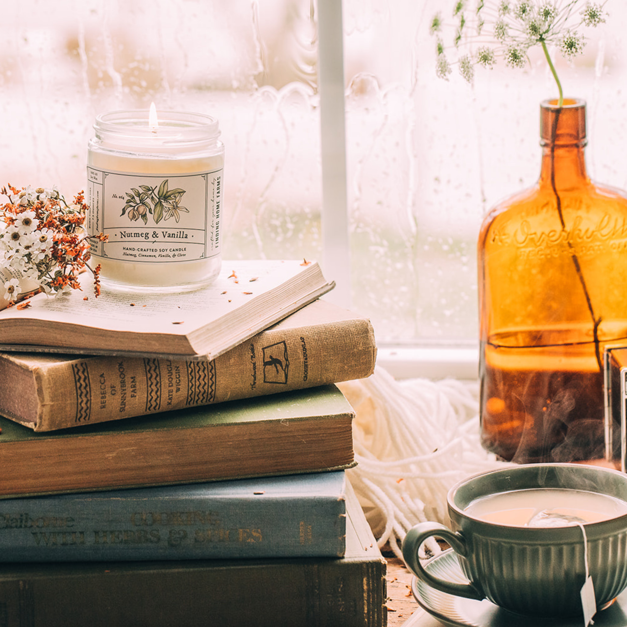Stack of books with a candle, mug, and bottle on a table