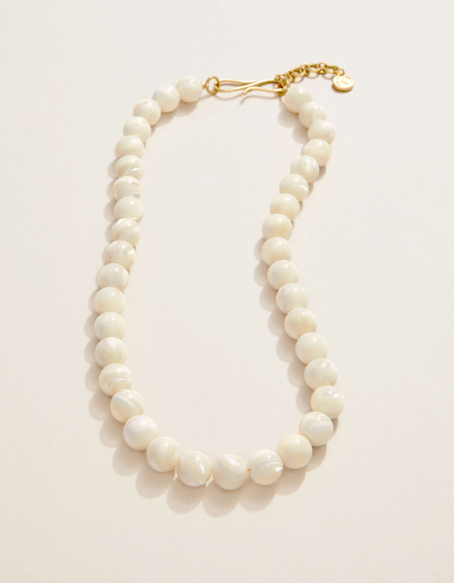 Pearl necklace with a gold clasp on a light pink background