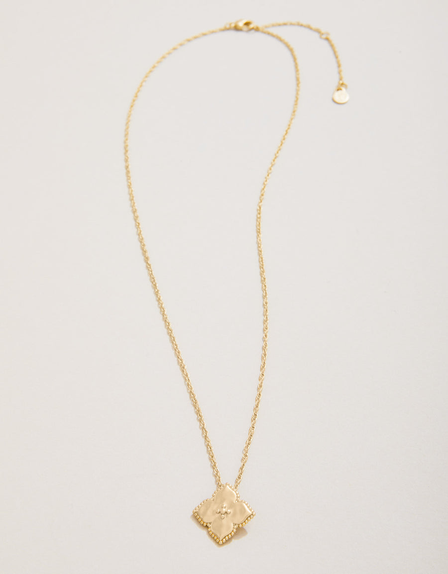 Gold necklace with a geometric pendant on a light gray background
