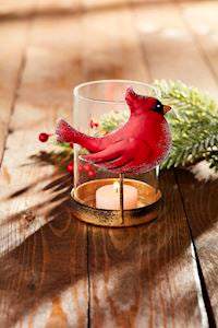 Red cardinal bird candle holder on a wooden surface with a blurred background