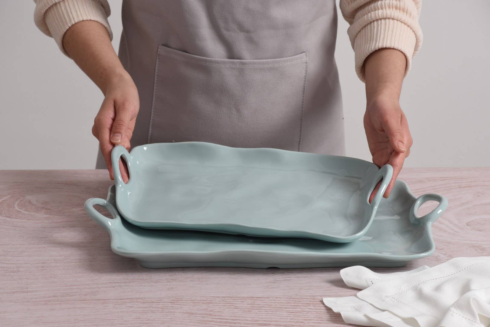 Person holding two light blue trays on a wooden surface
