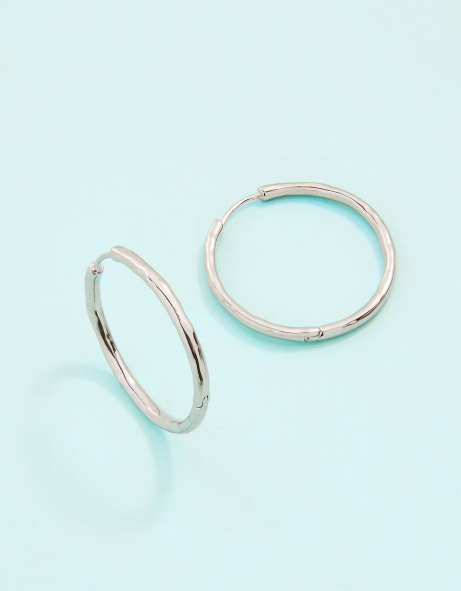 Two silver hoop earrings on a light blue background