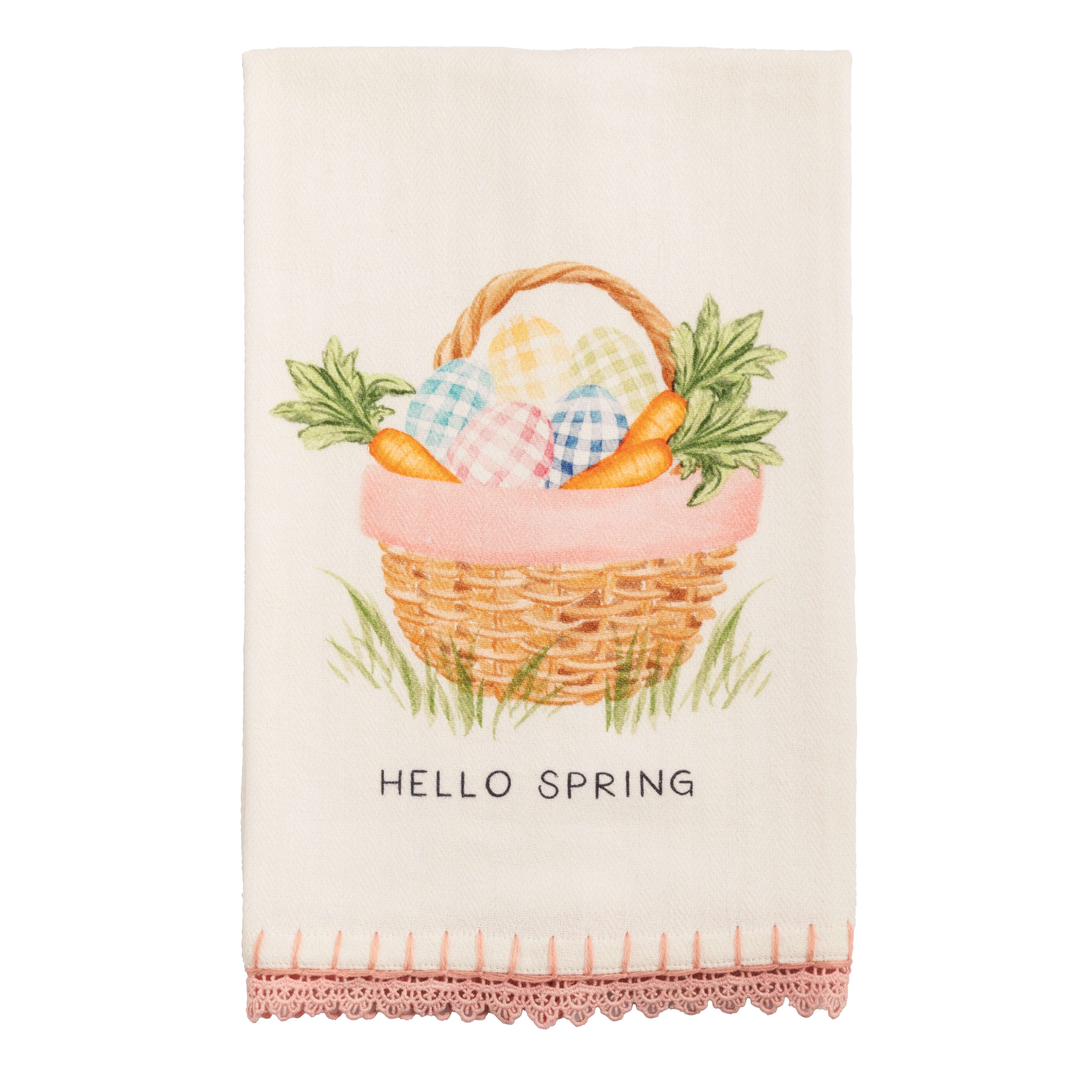 Tea towel with a spring-themed design featuring a basket, carrots, and eggs on a white background.