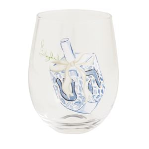 A clear stemless wine glass featuring a printed illustration of a blue and white dreidel with a small sprig of greenery, set against a plain white background.