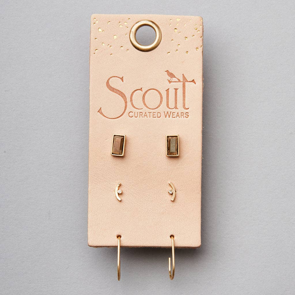 A pair of gold-colored stud earrings displayed on a beige card with 'Scout Curated Wears' branding and a small gold foil dot at the top.