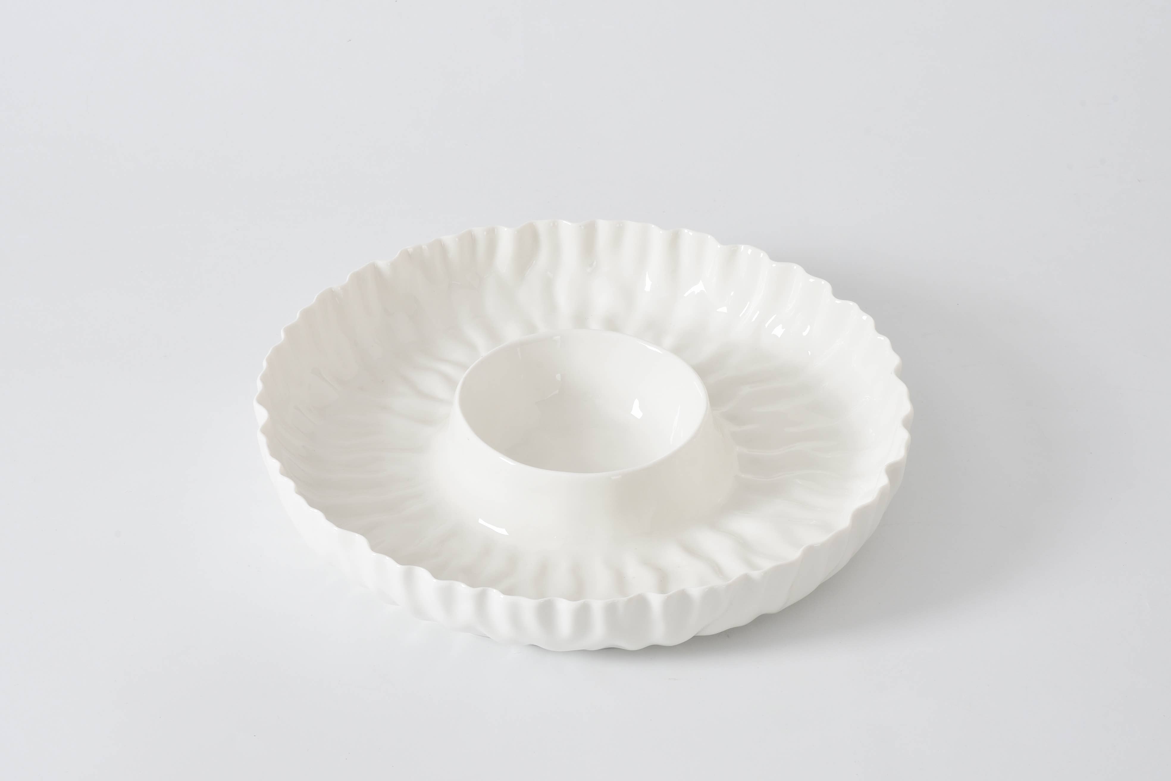 White ceramic dish with decorative rim on a light gray background