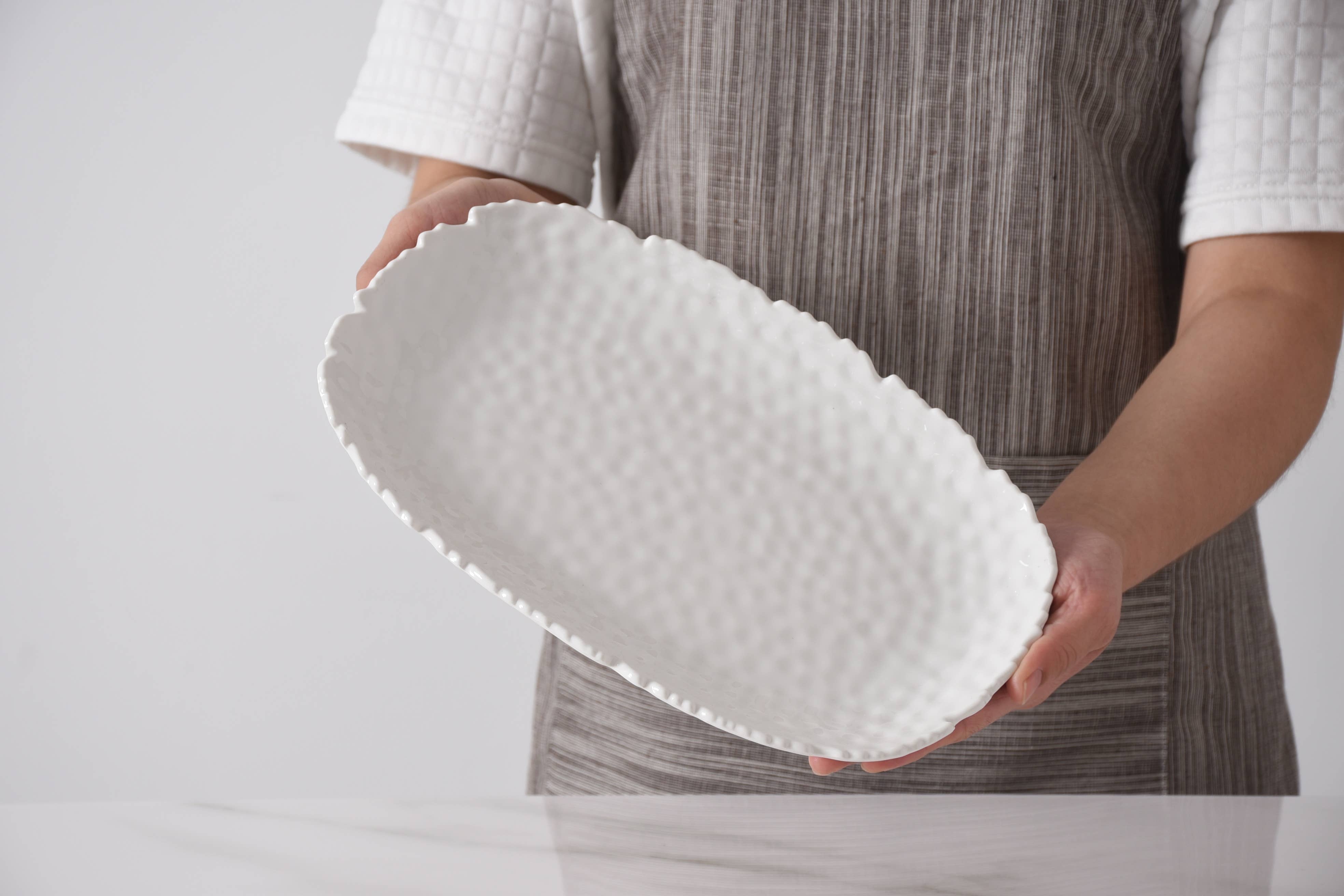 Person holding a textured white object against a plain background