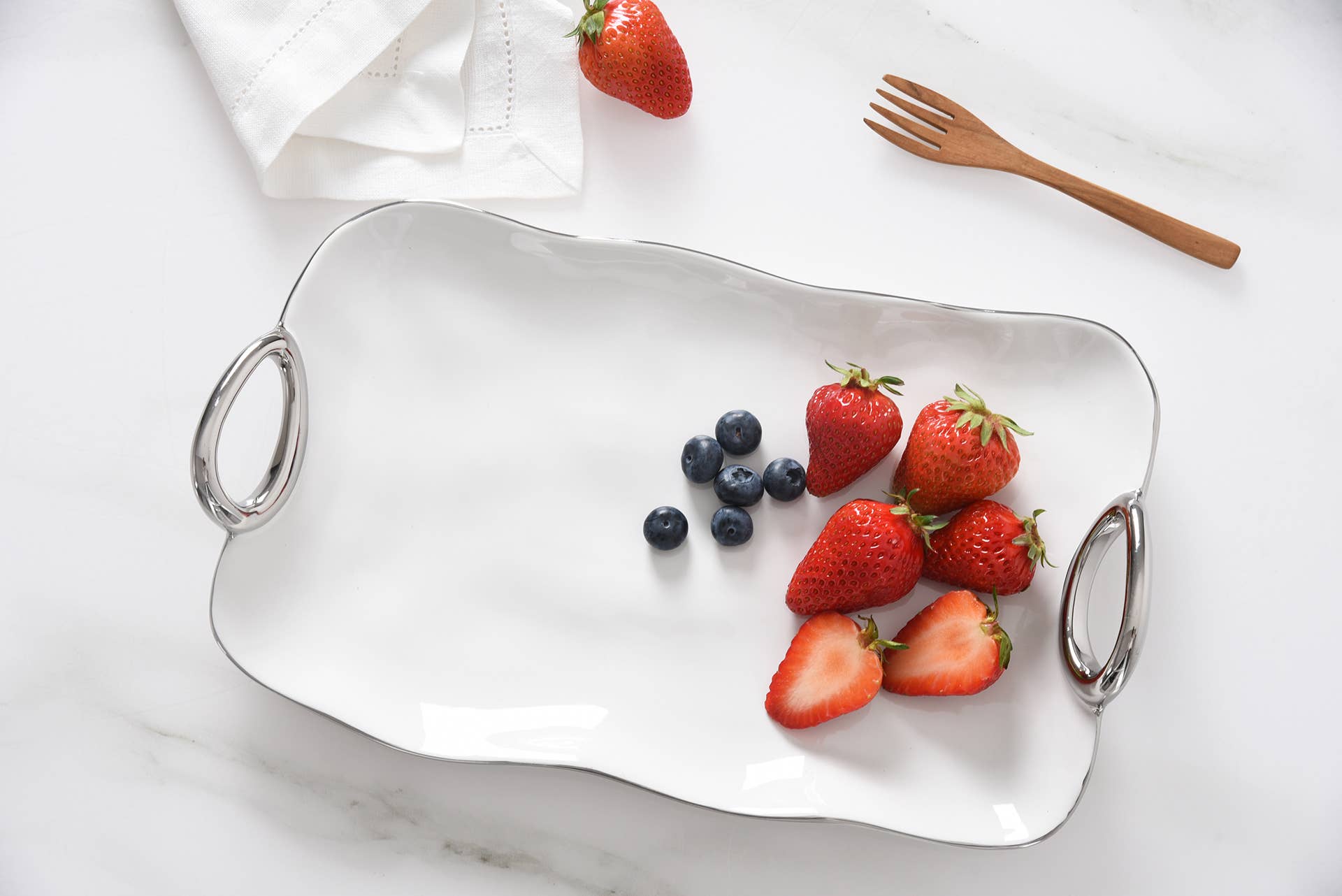 White serving tray with strawberries and blueberries on a marble surface