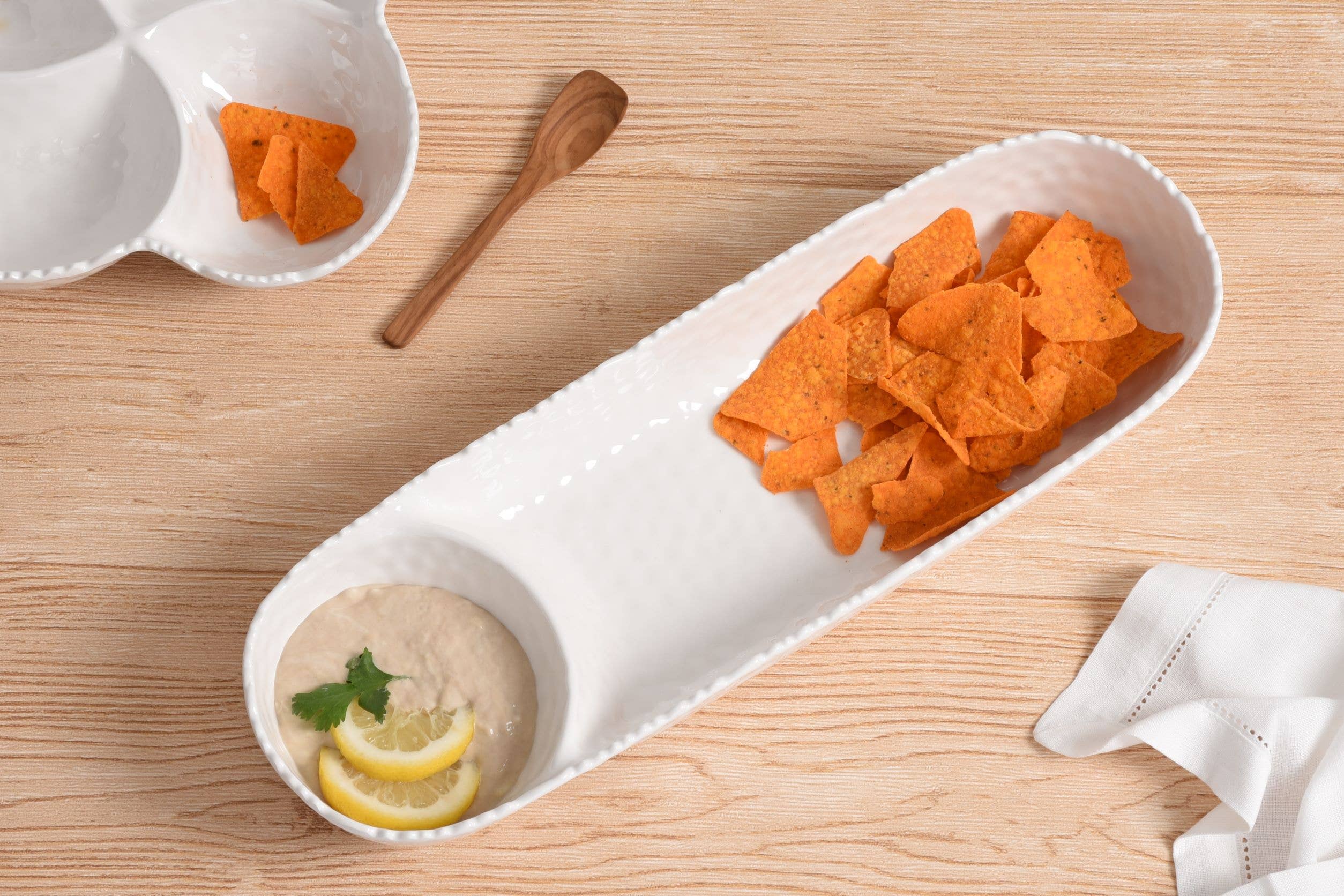 Dip and tortilla chips on a wooden table with a white plate.